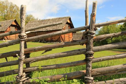 Keltenhaus auf einem Hügel mit grüner Wiese und Holzzaun
