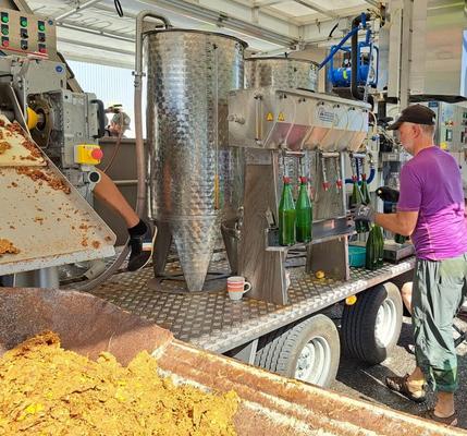 Mobile Saftpresse füllt Apfelsaft ab